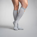 Gray knee-high socks with orange accents worn by a person on a gray background