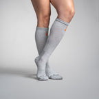 Gray knee-high socks with orange accents worn by a person on a gray background