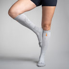 Gray knee-high socks with a brand logo worn by a person on a gray background