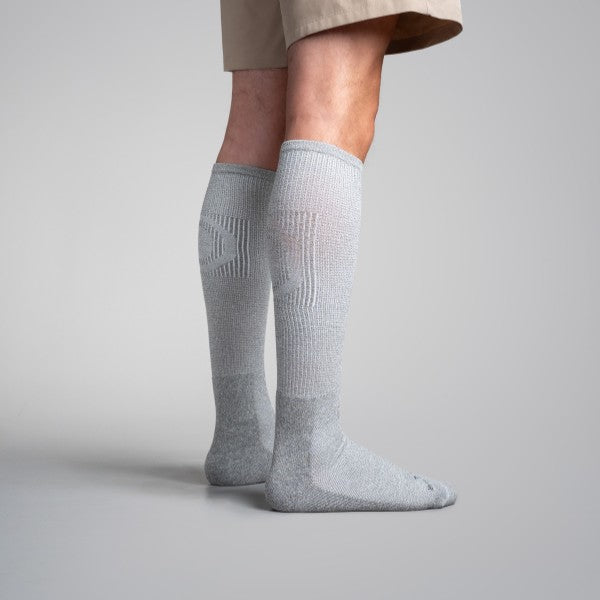 Gray knee-high socks worn by a person on a plain background