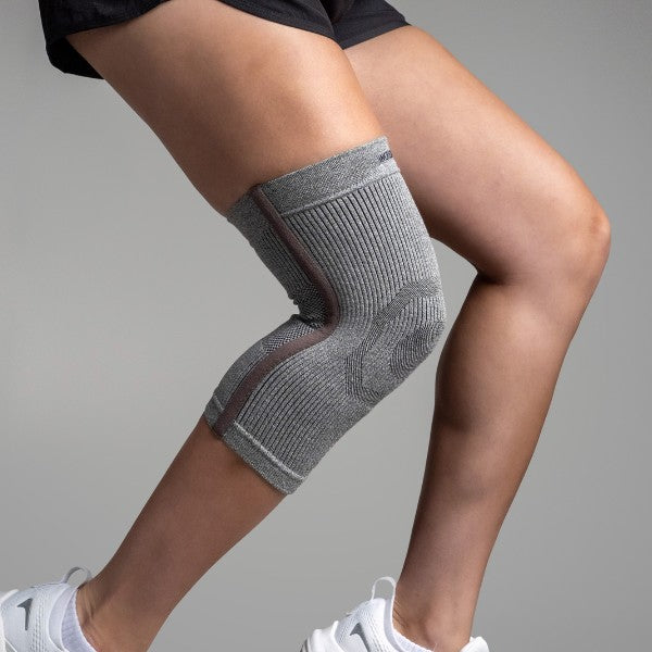 Person wearing a gray knee brace on a plain background