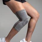 Person wearing a gray knee brace on a plain background