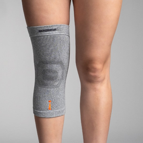 Gray knee brace on a person's knee with a plain background