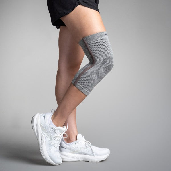 Person wearing a gray knee brace on a plain background