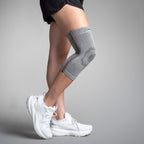 Person wearing a gray knee brace on a plain background