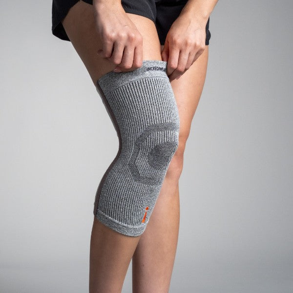 Person wearing a gray knee brace on a plain background