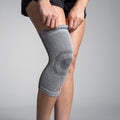 Person wearing a gray knee brace on a plain background