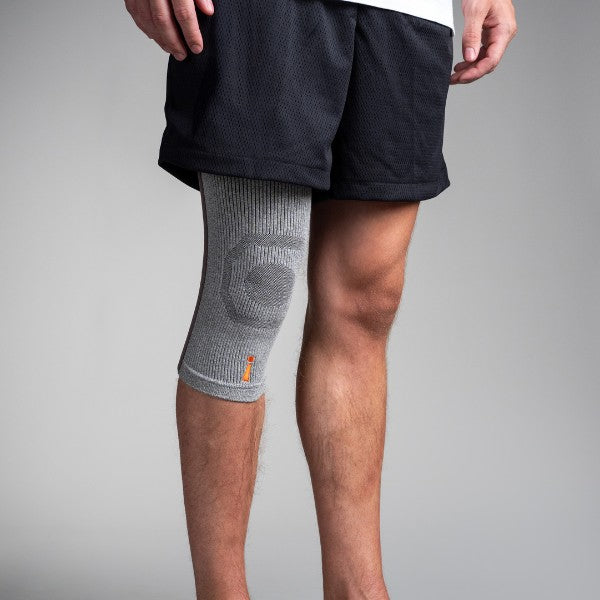 Person wearing a gray knee brace on a plain background