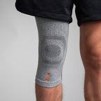 Gray knee brace on a person's knee against a light gray background