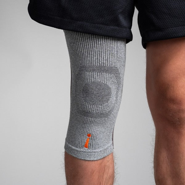 Gray knee brace on a person's knee against a light gray background