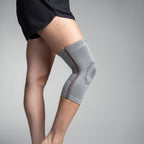 Gray knee brace on a person's knee against a gray background