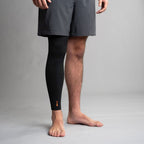 Person wearing a black compression leg sleeve on a gray background