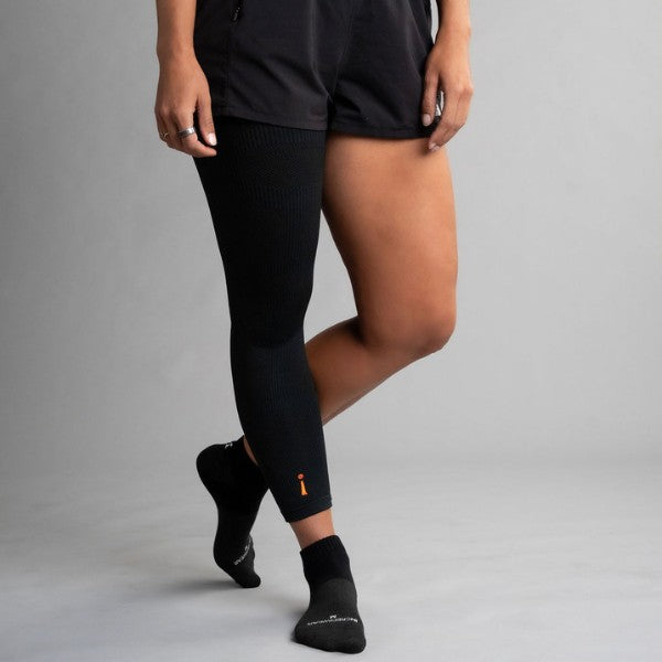 Person wearing black leg sleeve and socks on a gray background