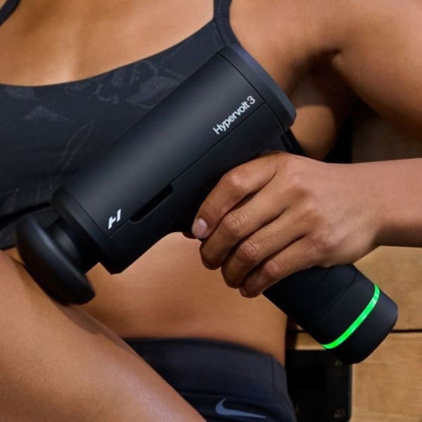 Person using a Hyperice device on their arm with a close-up view.