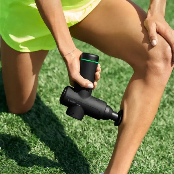 Person using a massage gun on their leg outdoors