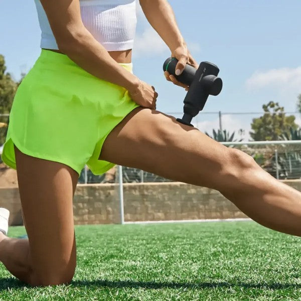 Person using a massage gun on their leg outdoors