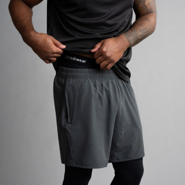 Person wearing black athletic shirt and black long pants with 'incrediwear' branding on a gray background
