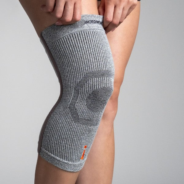 Gray knee brace on a person's knee with a plain background