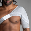 Man wearing a shoulder brace against a gray background