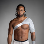 Man wearing a shoulder brace against a gray background