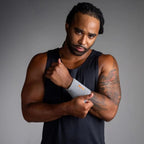 Man wearing a black tank top and gray wristband against a gray background