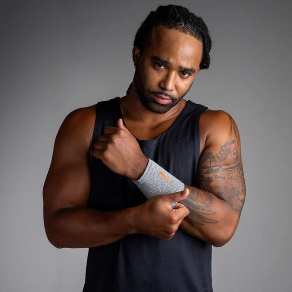 Man wearing a black tank top and gray wristband against a gray background